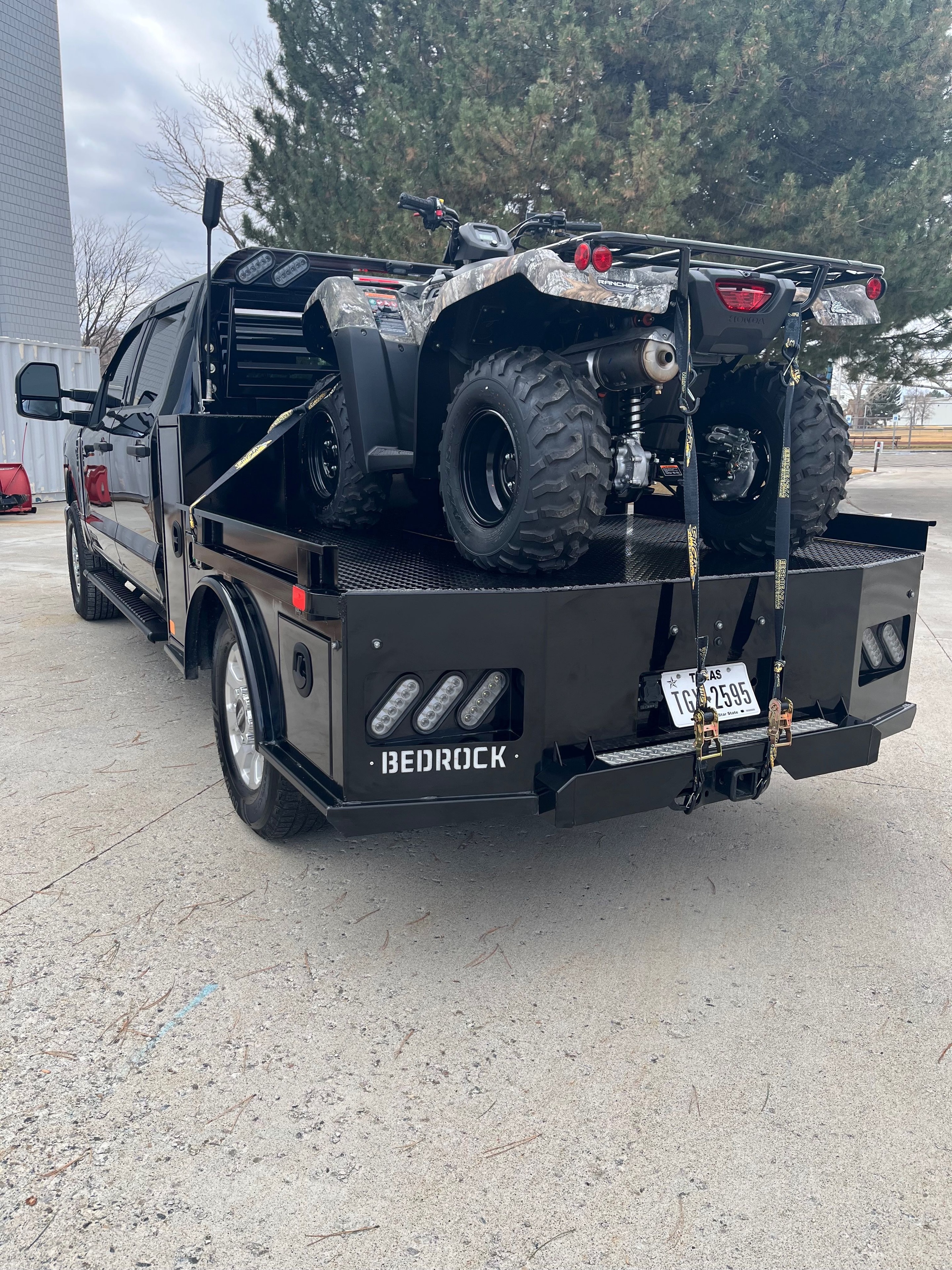 Bedrock Granite Plus flatbed loaded with an ATV — showing tie-down points and toolboxes